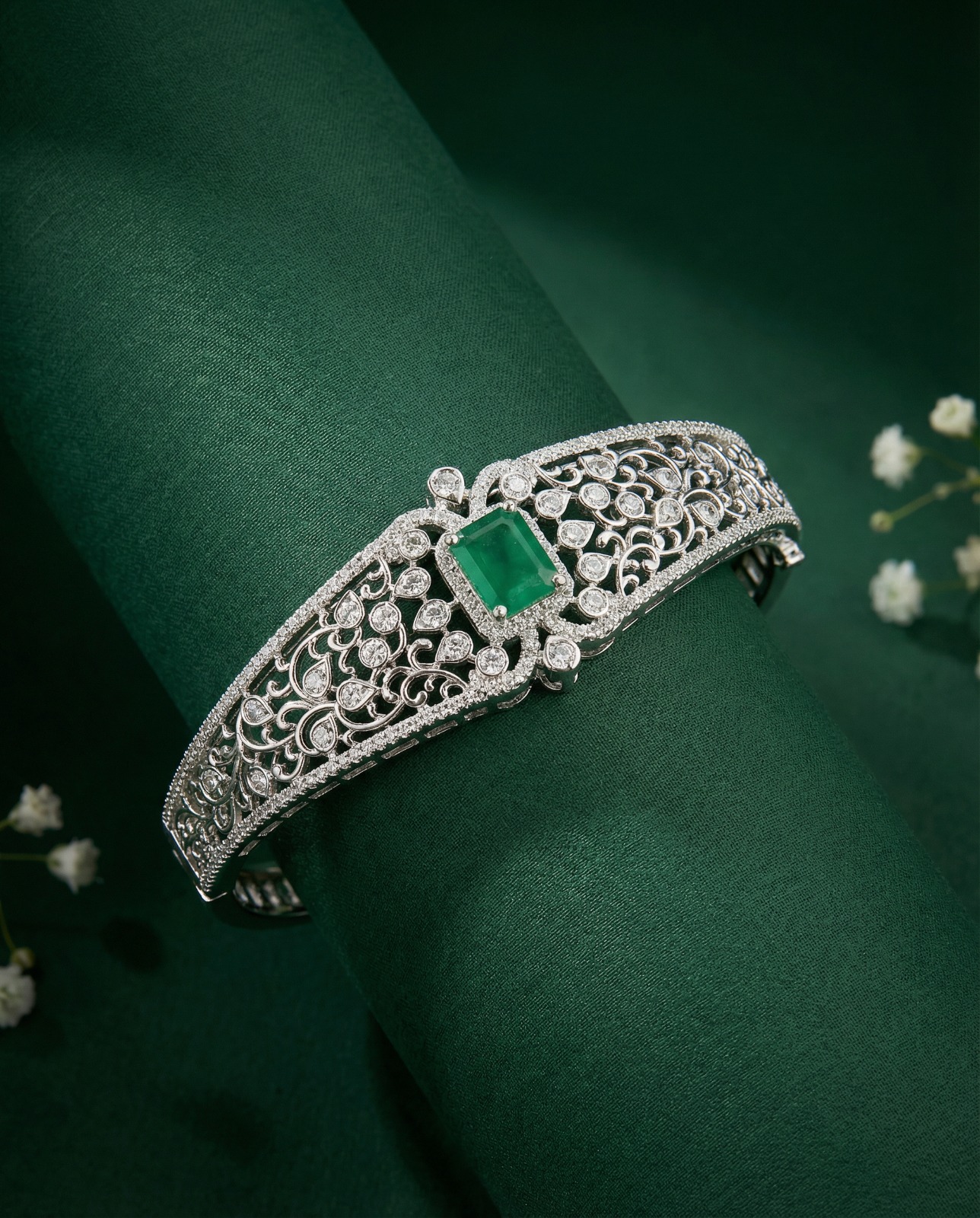 AI-generated emerald and diamond cuff bracelet on green velvet with white flowers