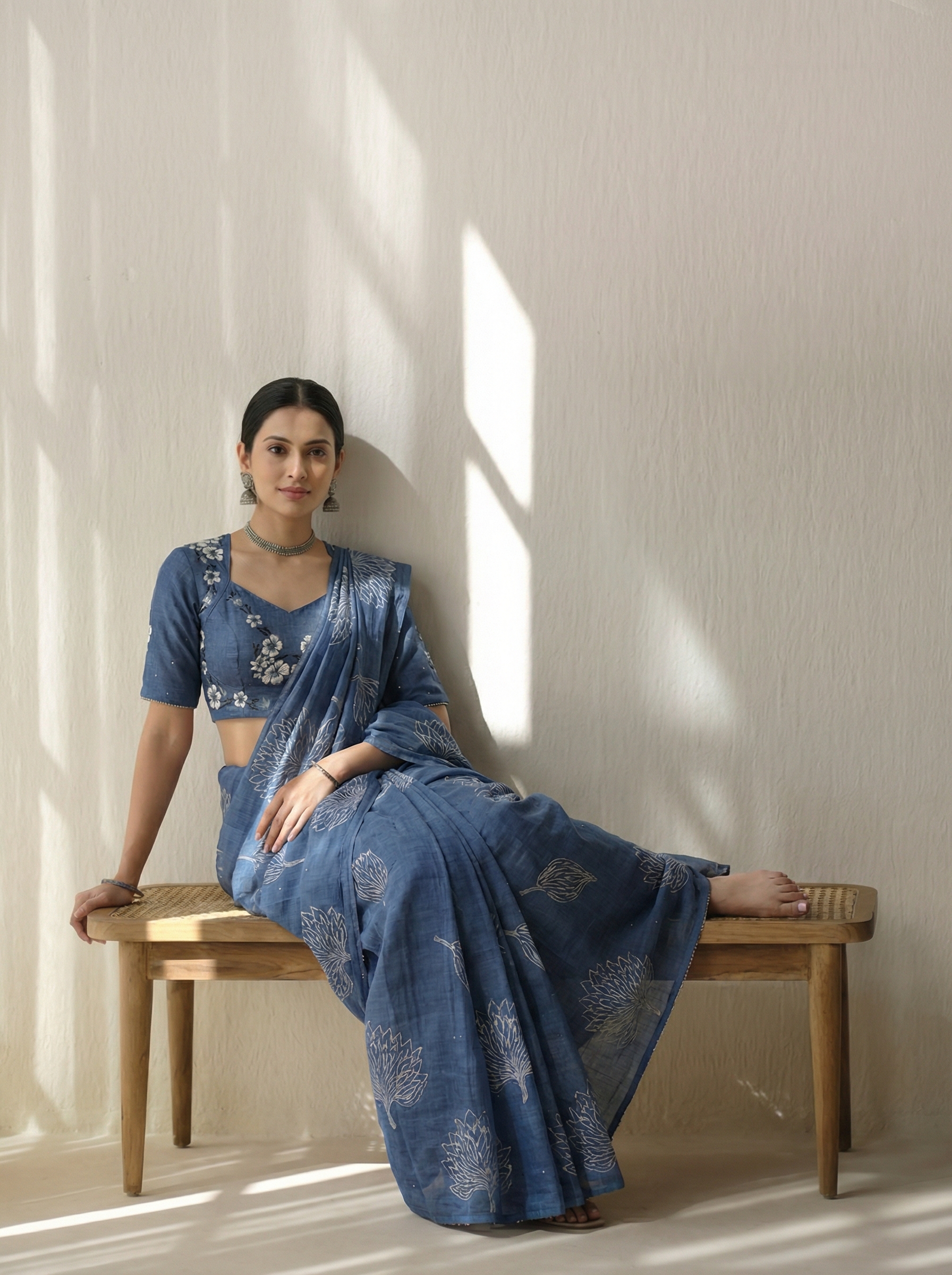 AI-generated fashion visual of a woman in a blue printed saree seated on a wooden bench