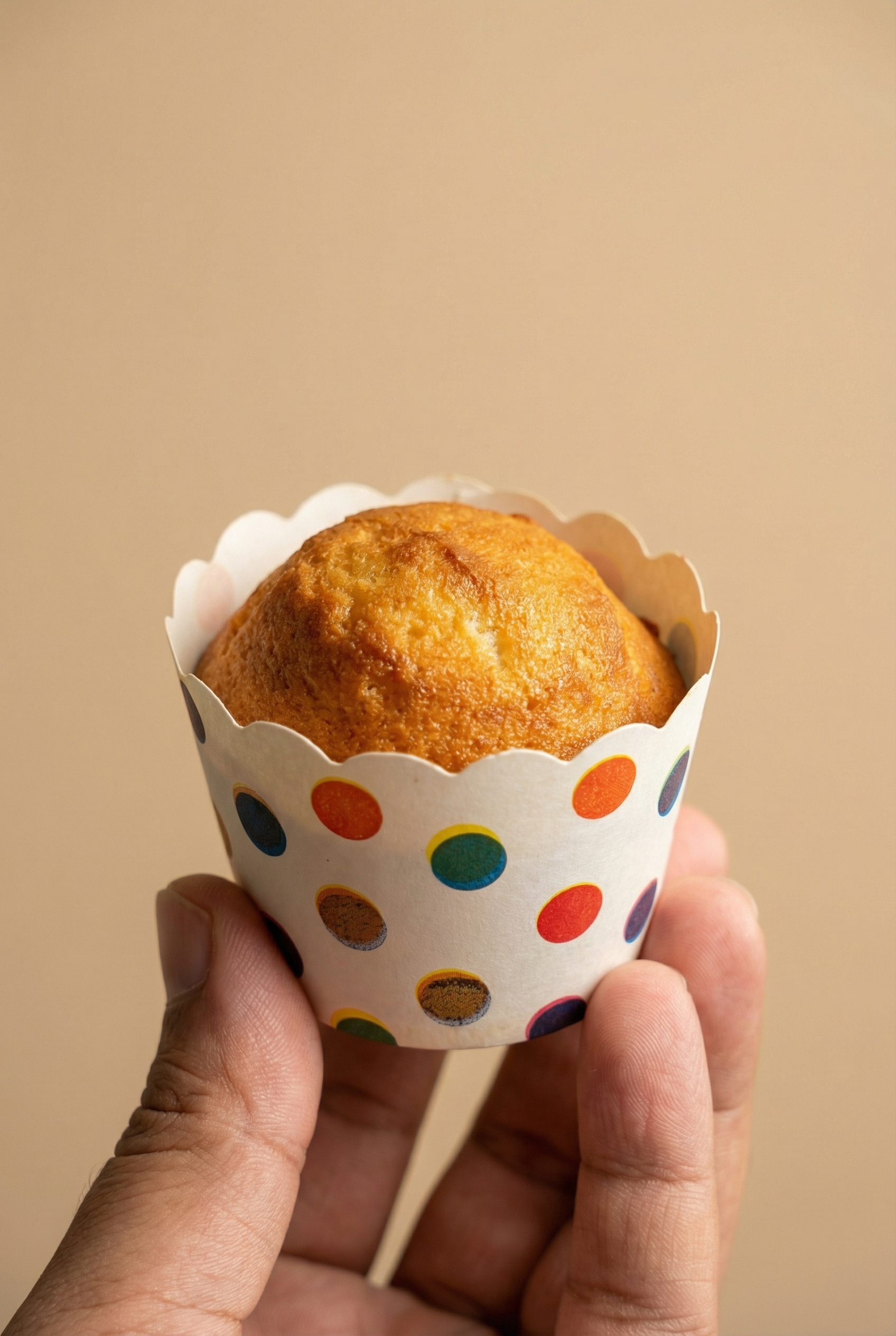 AI-generated product visual of a hand holding a polka-dot wrapped muffin